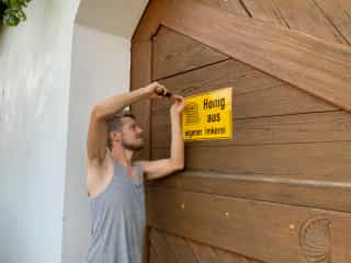 Matthias montiert das Schild 'Honig aus eigener Imkerei'