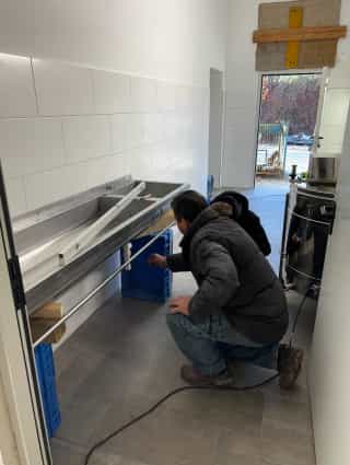 Matthias und sein Vater installieren das Edelstahlwaschbecken im neuen Honigverarbeitungsraum