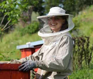 Portrait von Romi Netzberger bei der Bienenarbeit