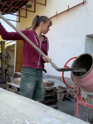 Romi Netzberger shovels sand into the concrete mixer