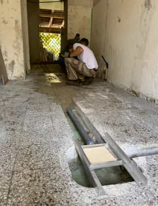 In the future honey processing room, Matthias and his father are laying water pipes in the floor and wall